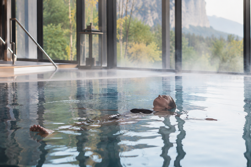 Frau floatet in einem Innenpool mit toller Panoramaaussicht